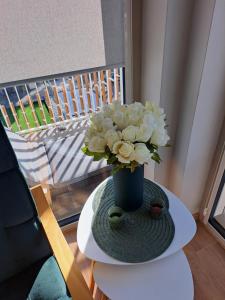 un jarrón azul con flores blancas en una mesa en Rubus 305 Sofii en Świnoujście