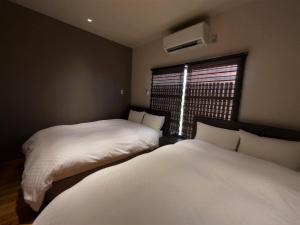 2 camas en una habitación pequeña con ventana en Kamozen Kyoto Machiya Stay en Kioto