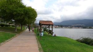 a group of people sitting on the grass near a lake at ATICO muy luminoso e increíbles vistas in Baiona