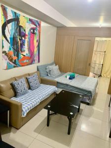 馬尼拉的住宿－Kathys crib 32sqm Condo Shell Residences，一间配有沙发、一张桌子和一幅画的房间