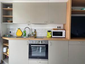 Studio - Centre de Villefranche de Lauragais في فيلفرانش-دو لوراجيه: مطبخ بخزائن بيضاء وموقد وميكروويف