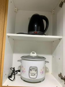 a slow cooker on a shelf with a pot on it at Kathys crib 32sqm Condo Shell Residences in Manila