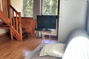 a living room with a tv and a bed and a table at Duplex 4/6p Le Familial in Laveissière