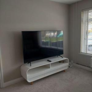 a flat screen tv sitting on top of a white entertainment center at Sunny room in a modern house in Cardiff