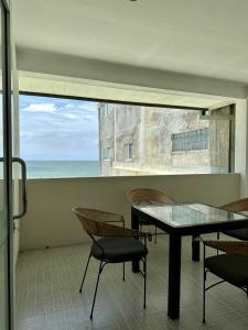 a table and chairs in a room with a view of the ocean at Ripple Reach Apartments in Galle