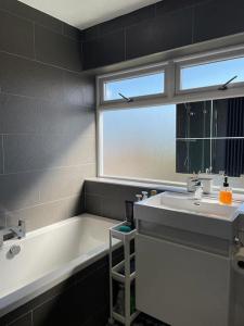 a bathroom with a tub and a sink and a window at Sunny room in a modern house in Cardiff