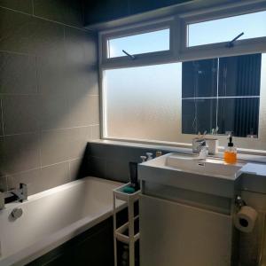 a bathroom with a sink and a tub and a window at Sunny room in a modern house in Cardiff