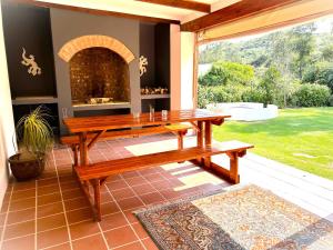 a wooden bench on a patio with a fireplace at Adrenalin Addo Manor House in Addo