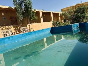 a pool of water with chairs and a building at Gagal camp in Siwa