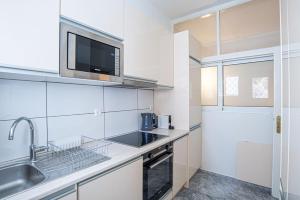 cocina blanca con fregadero y microondas en Hermes Apartments, 2 bedrooms, great facilities! en Athens