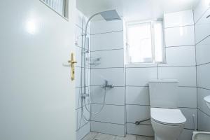 La salle de bains blanche est pourvue de toilettes et d'une fenêtre. dans l'établissement Hermes Apartments, 2 bedrooms, great facilities!, à Athènes