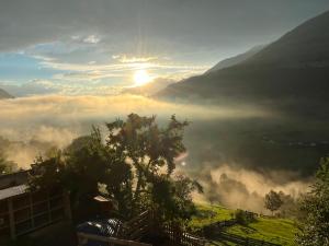 a view of a foggy valley with the sun in the sky at Apart Alpenzeit in Arzl im Pitztal