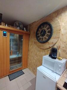 a kitchen with a clock on the wall and a refrigerator at Gîte Sauna Balnéo Berck sur Mer Lâchez Prise in Berck-sur-Mer