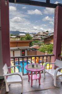 un patio con mesa, sillas y piscina en K-Bunk Hostel Pai Walking Street, en Pai