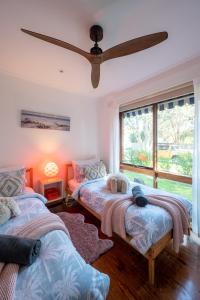 two beds in a room with a ceiling fan at Fun Filled Renovated 80's Gem, 400m to Beach! in Torquay