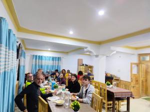 un grupo de personas sentadas en una mesa en un restaurante en Himalayan Regal House, en Deskit