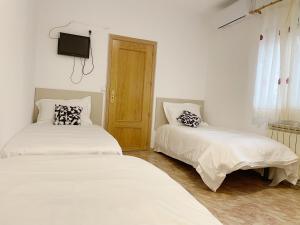 two beds in a room with a tv on the wall at Pensión el Carmen in Alcobendas +24 photos