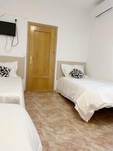 アルコベンダスにあるPensión el Carmenのベッド2台と木製のドアが備わる客室です。