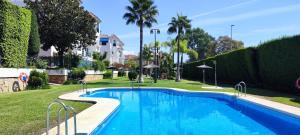 a swimming pool in a park with trees and bushes at Apartamento playa - Puerto Banus in Marbella