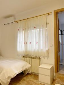 a bedroom with a bed and a window with white curtains at Pensión el Carmen in Alcobendas