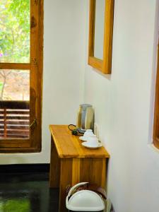 y baño con aseo, mesa de madera y ventana. en Sunbird's Home, en Udawalawe