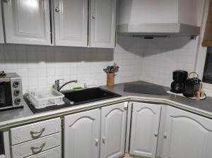 una cocina con armarios blancos y fregadero en Landaise en Tarnos