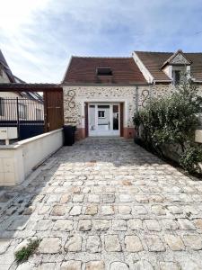 une maison avec une allée en pierre en face d'un garage dans l'établissement la petite maisonnette, à Le Plessis-Feu-Aussoux