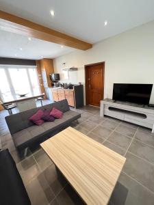 a living room with a couch and a flat screen tv at la petite maisonnette in Le Plessis-Feu-Aussoux