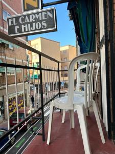 dwa białe krzesła siedzące na balkonie budynku w obiekcie Pensión el Carmen w mieście Alcobendas