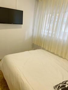 a bedroom with a bed with a television on the wall at Pensión el Carmen in Alcobendas