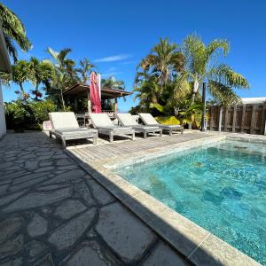 a swimming pool with lounge chairs and an umbrella at La Villa Miranda Meublé de Tourisme 4 * in Saint-Gilles les Bains