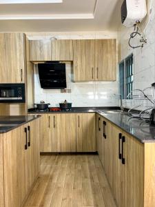 a kitchen with wooden cabinets and black counter tops at Sparkles Apartments in Abuja