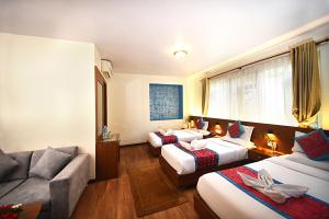 a hotel room with three beds and a couch at Hotel Amaryllis Kathmandu in Kathmandu