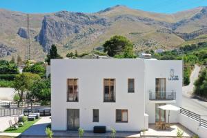 a white house with mountains in the background at LA DAMA in San Vito lo Capo