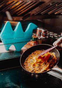 una persona cocinando comida en una sartén en un horno en W Muscat en Mascate