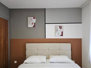 - une chambre avec un lit blanc et deux photos sur le mur dans l'établissement LUX APARTMAN ELENI ROOMS,oaza mira i tisine u centru Vrnjačke banje, à Vrnjačka Banja