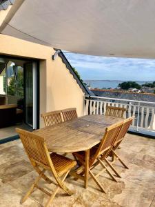 een houten tafel en stoelen op een balkon bij Les chambres du Roc'h Hir à Loguivy de la Mer in Ploubazlanec