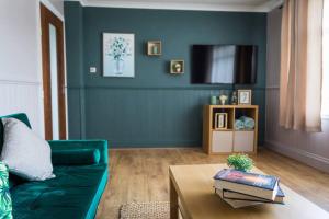 a living room with a green couch and a table at Comfort at Keldy in Tettenhall