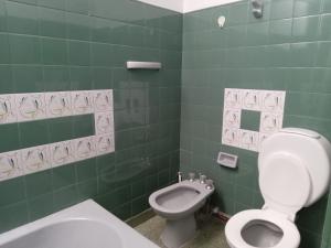 a green tiled bathroom with a toilet and a bidet at L&J Departamento in Gerli