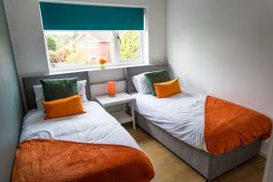 two beds in a room with a window at Comfort at Keldy in Tettenhall