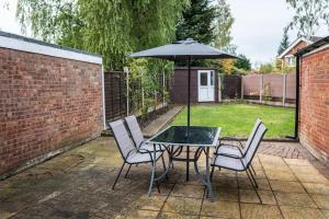 a table and chairs with an umbrella on a patio at Comfort at Keldy in Tettenhall