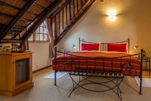 a bedroom with a bed with red pillows and a tv at Klein Paradijs Country Retreat in Pearly Beach