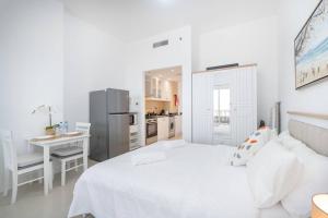 a white bedroom with a white bed and a kitchen at Serene Studio & Sea View & Brand New Listing in Ras al Khaimah