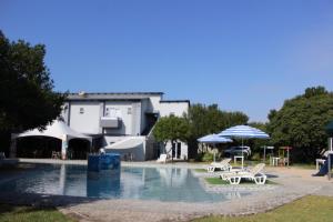 a swimming pool with tables and umbrellas in front of a building at Ecolux in Marracuene