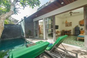 a patio with a pool and chairs next to a house at Sari Dana Villas in Sanur