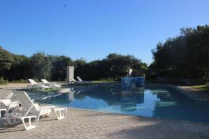 a swimming pool with white chairs next to it at Ecolux in Marracuene