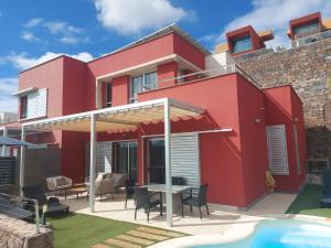 een rood huis met een patio en een zwembad bij Villa Vista Golf Salobre - Maspalomas self-sufficient with pool heating in Maspalomas
