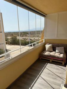 - un balcon avec un canapé en face d'une grande fenêtre dans l'établissement Piso familiar en El Toyo, à Almería