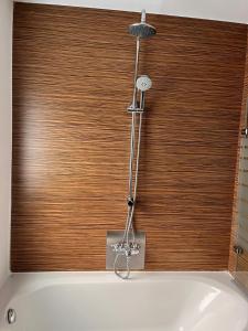a bath tub with a shower in front of a wooden window at Ferienhaus nähe Legoland 4-h3rOeS in Leipheim