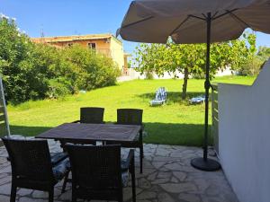 einen Tisch und Stühle mit Sonnenschirm auf einer Terrasse in der Unterkunft Foivos Seaside Apartments in Agios Georgios